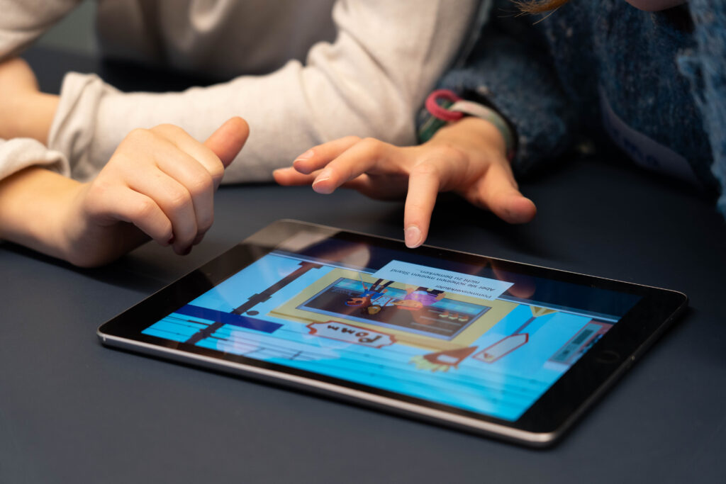 Zwei Kinder spielen ein Lernspiel auf einem Tablet.